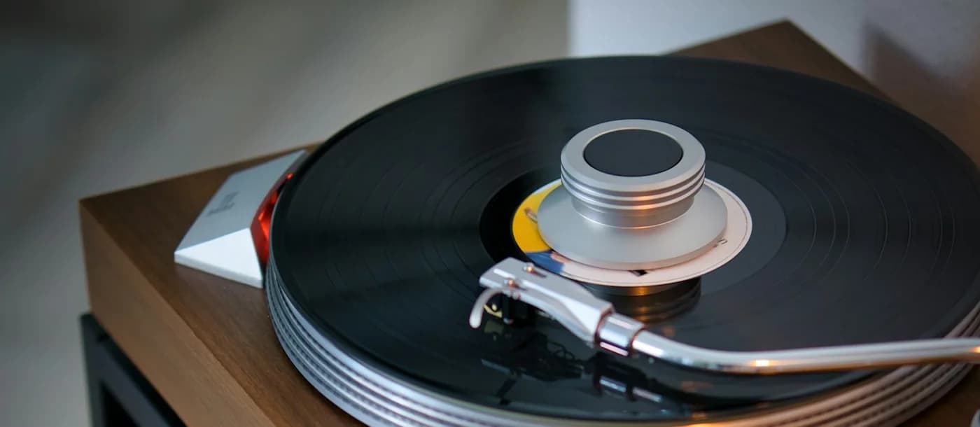 Direct-drive turntable with a walnut plinth playing a record atop a vintage hi-fi stack